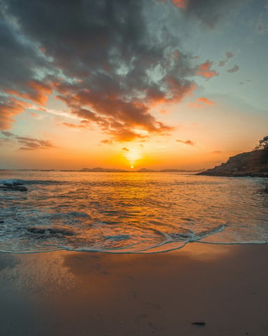 Dramatic golden sunset over a Mexican beach with waves and rocky headland