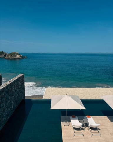 Infinity pool with loungers overlooking a private beach and rocky islet in Mexico