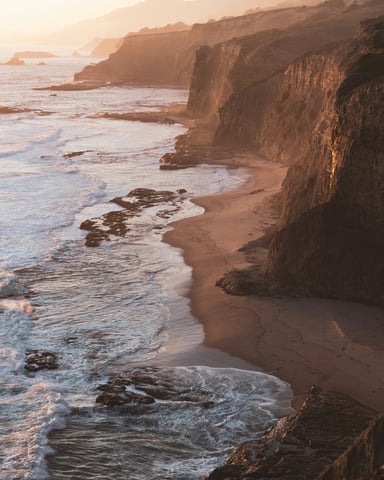 Warm golden light on coastal cliffs and beach at sunset