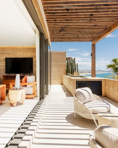 Modern terrace with wooden pergola, lounge seating, and panoramic ocean and coastline views
