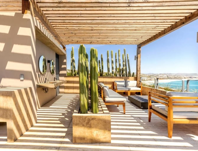 Wooden pergola terrace with cactus planter, lounge chairs, and turquoise sea view